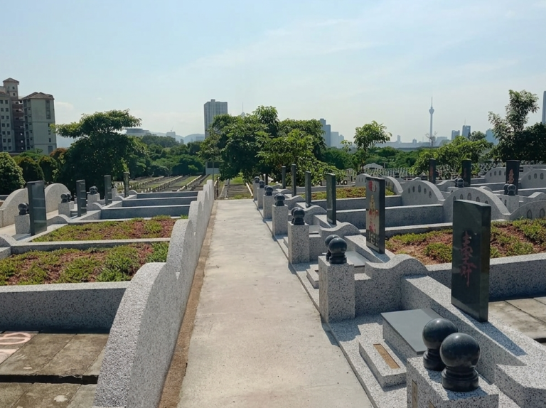 Rows of well-maintained burial plots at Kwong Tong Cemetery with KL skyline in the background